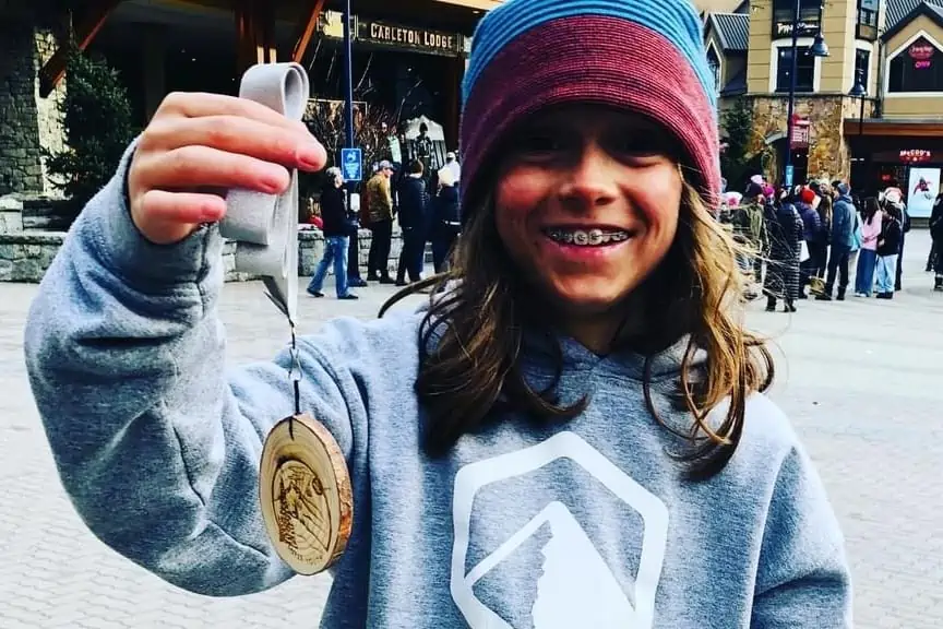 A young skier holding a medal