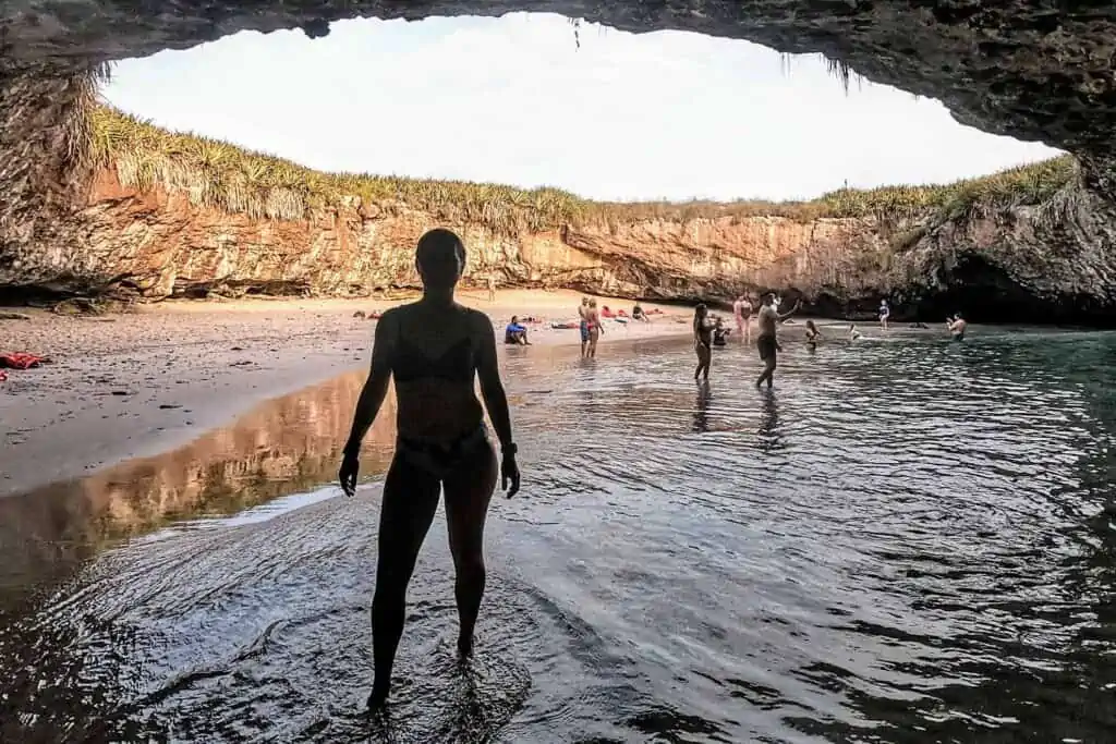 A woman standing in the water in a cave opening