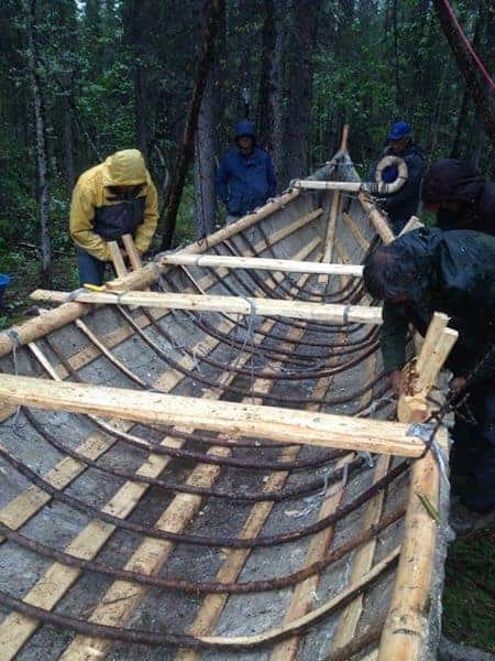 Dene men constructing a traditional moose skin boat